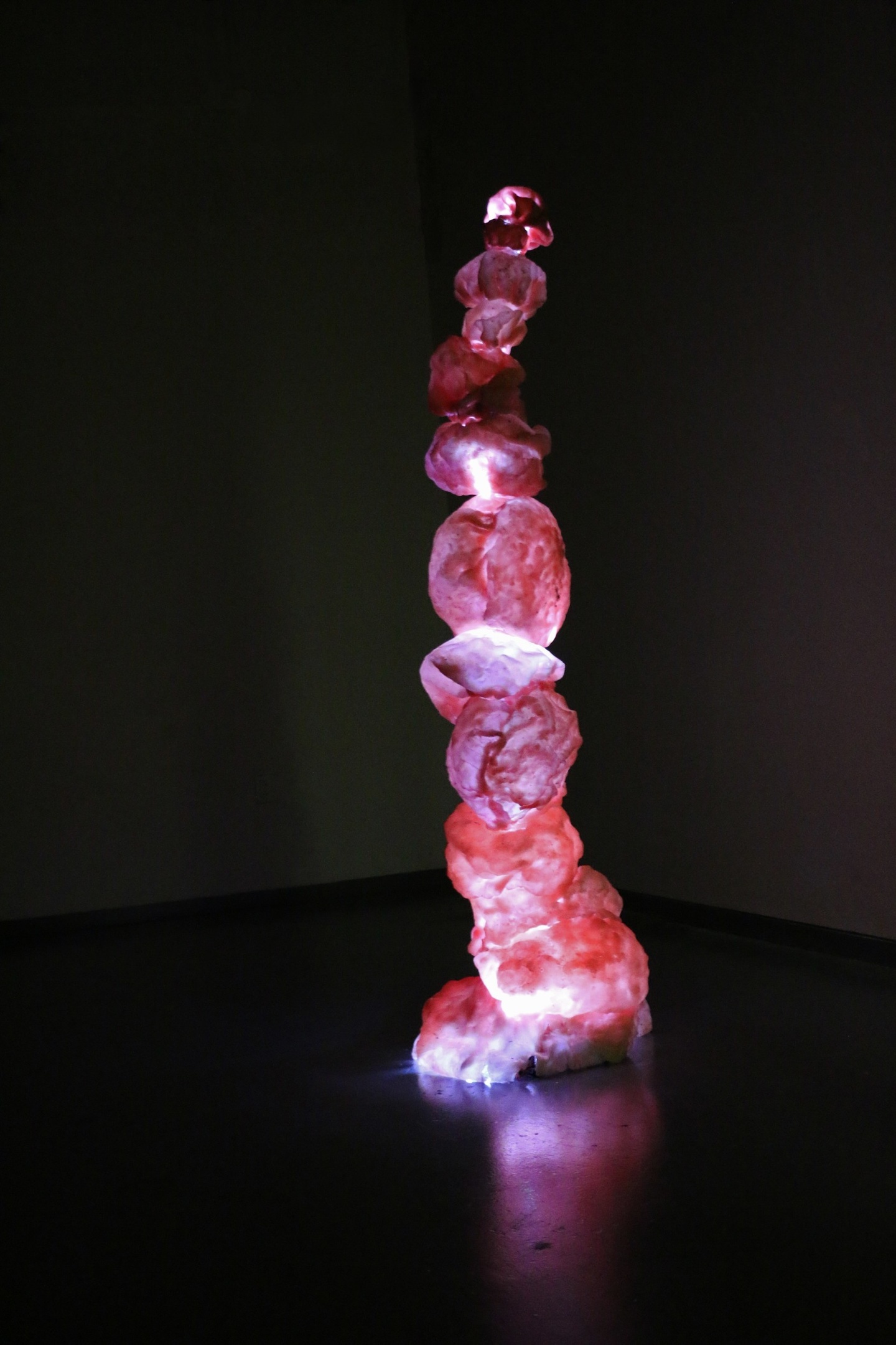 A cluster pile of mushroom-like tube coral made from pale pink paper illuminated from the inside 