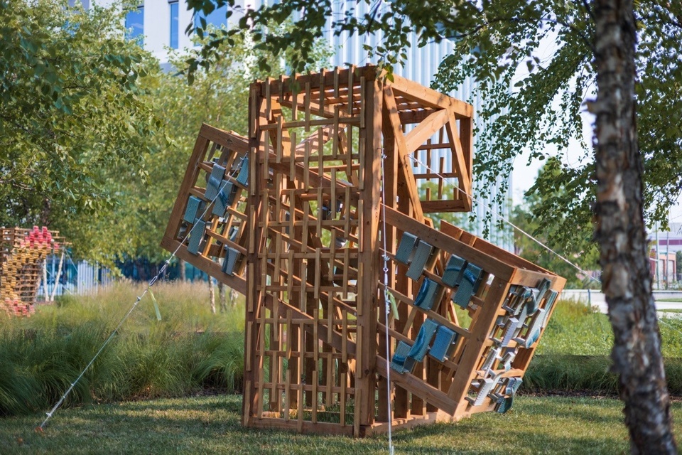 Wood and ceramic sculpture outdoors with native grasses and trees