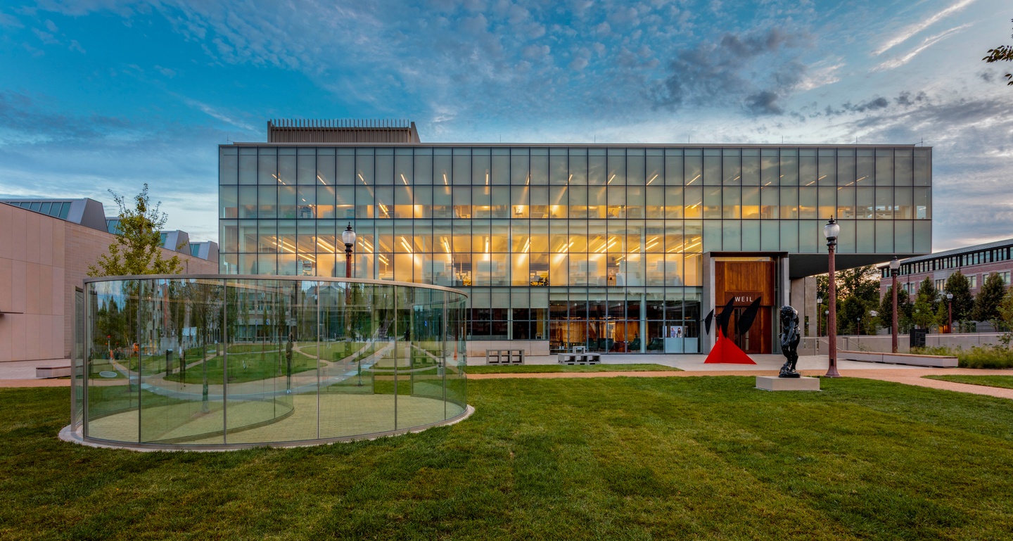 Various large sculptures in front of an illuminated glass building