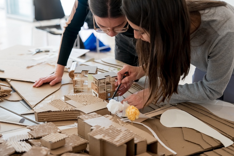 Two students work on a detail on a cardboard architectural model