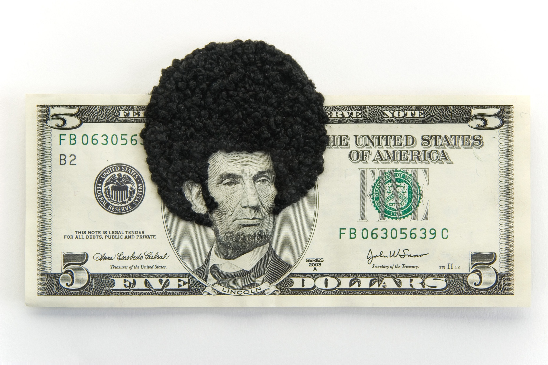 A five dollar bill with an afro of black thread overlaying Abraham Lincoln's head.