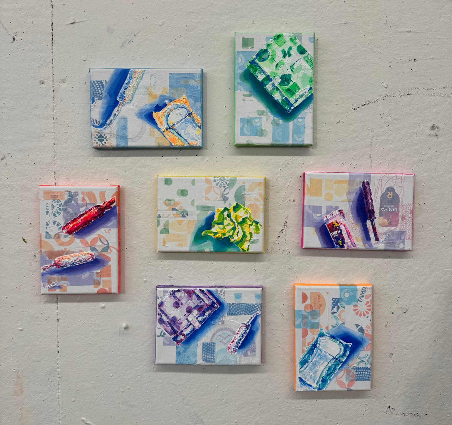 Paintings of female sanitary products on canvases overlaid with product wrappers and packaging.