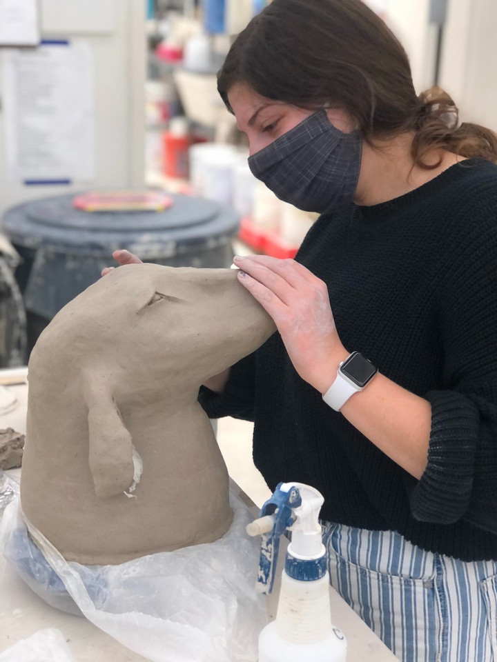 A student models the head of an animal out of clay