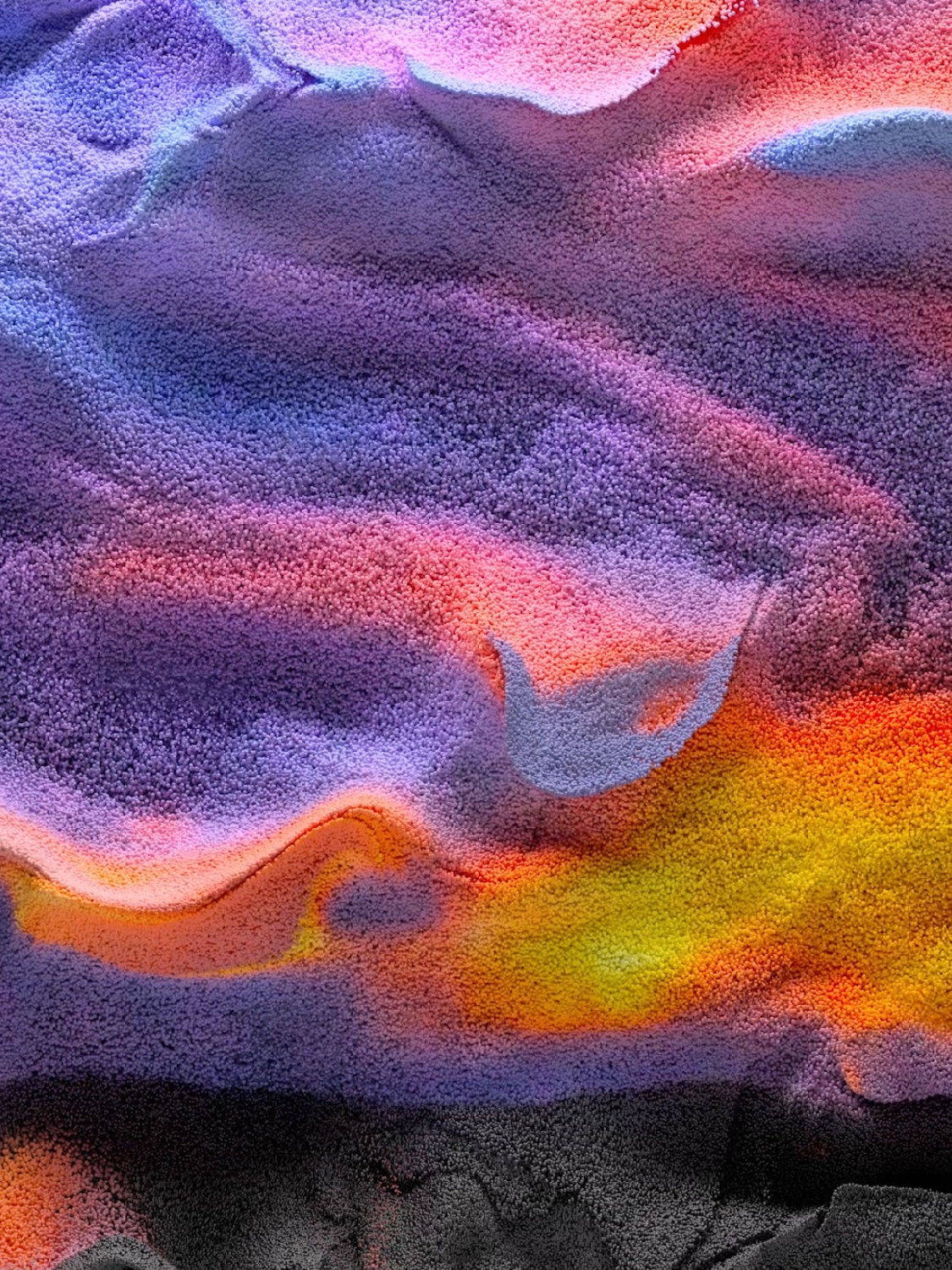 An abstract image that resembles a sandy landscape in the pink, purple, and orange hues of a desert sunset