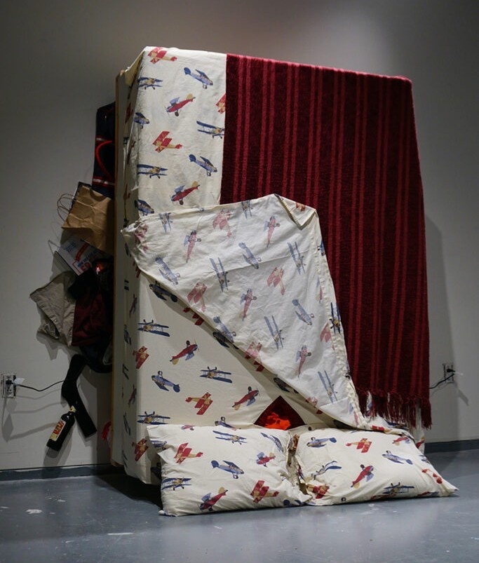 A red and patterned upside down mattress against a gallery wall