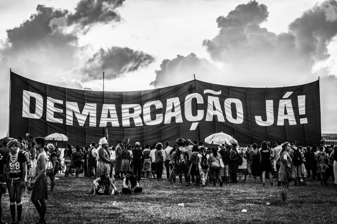 black and white photo of group of people outside holding large sign demarcacao ja!