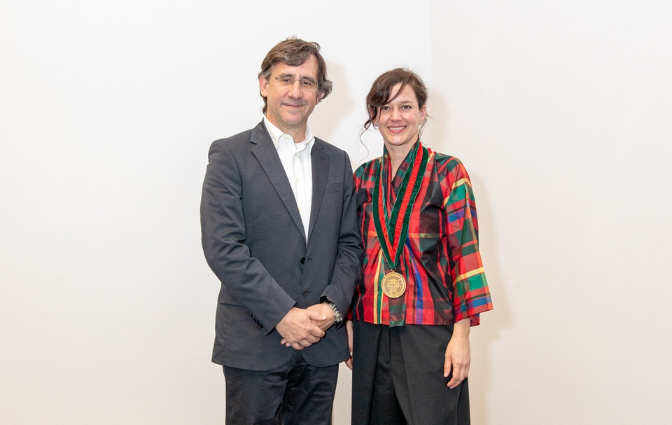 Man and woman standing next to each other. The woman has a medallion around her neck.
