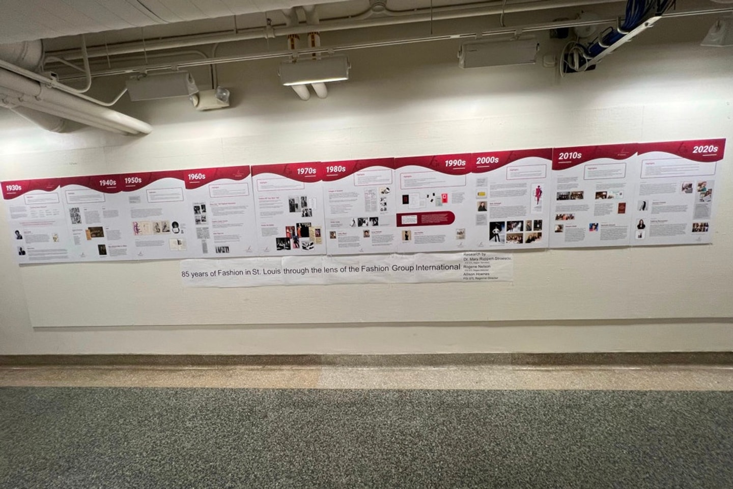 Large-scale timeline posted to a wall in a long hallway, highlighting work by Fashion Group International