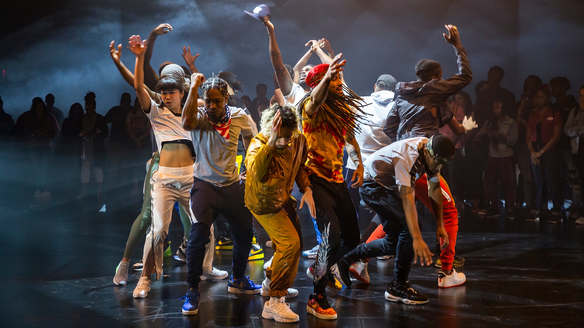 Maze dancers gathered together dancing in the middle of a black box theater