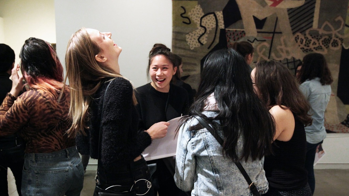People in front of an abstract artwork talking and laughing