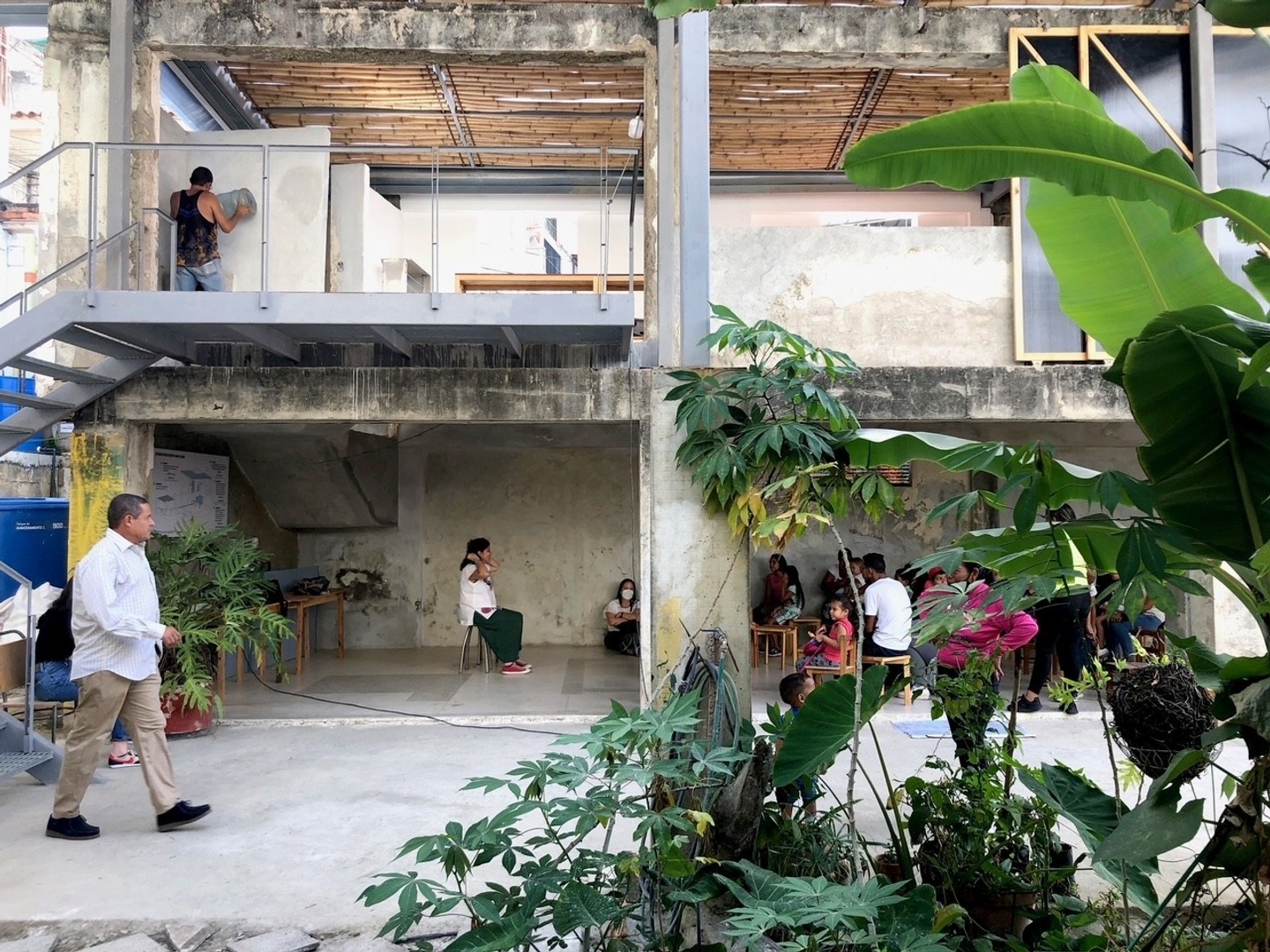 Man walking through open-air building with plant in foreground