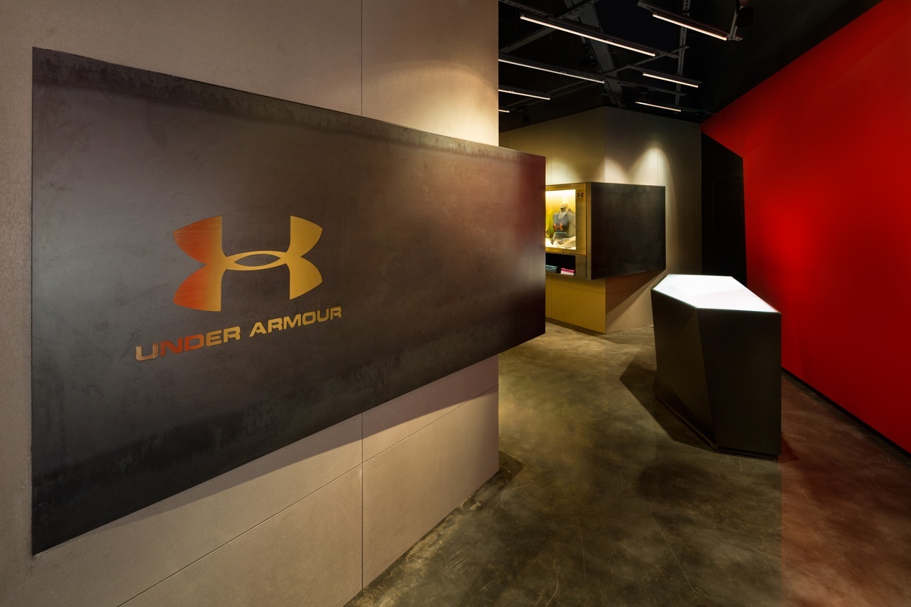 Image of the entrance experience of the branded space, with the Under Armour logo on the left on a plaque