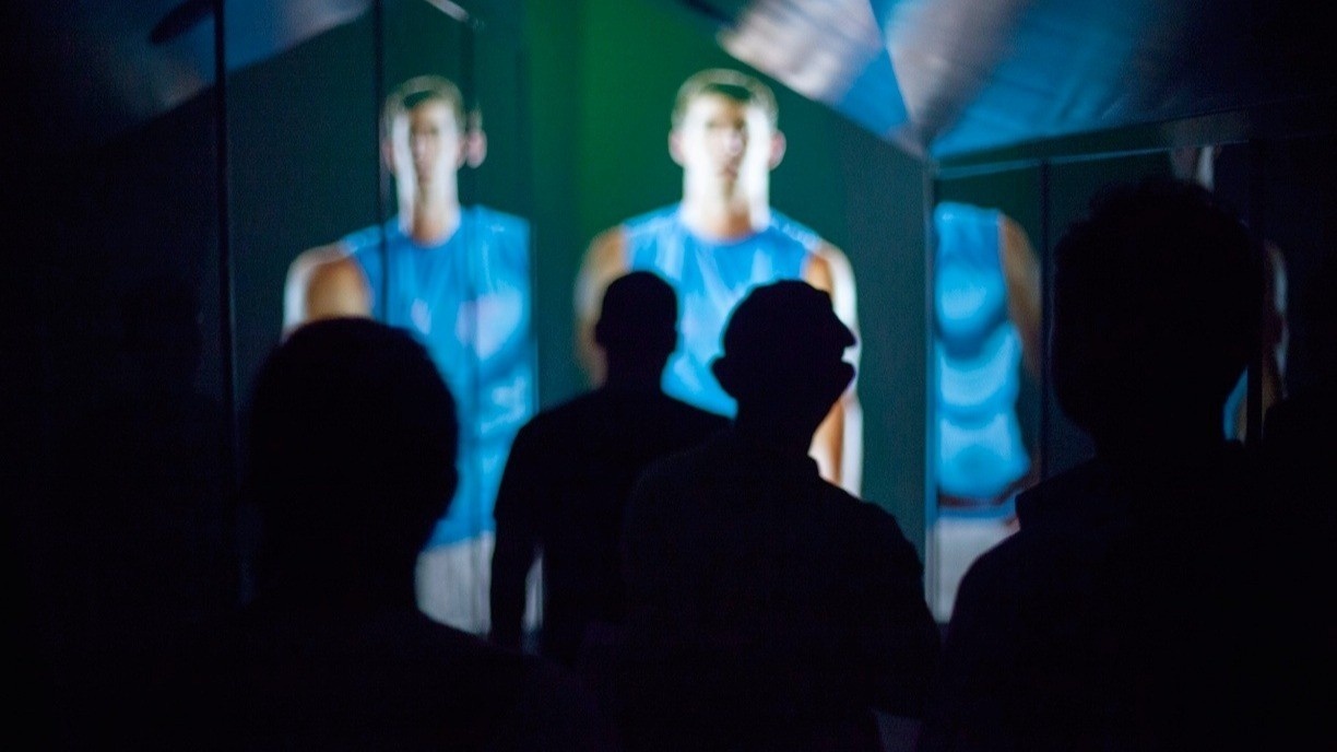 People standing in a dark room with Michael Phelps of angled digital surfaces
