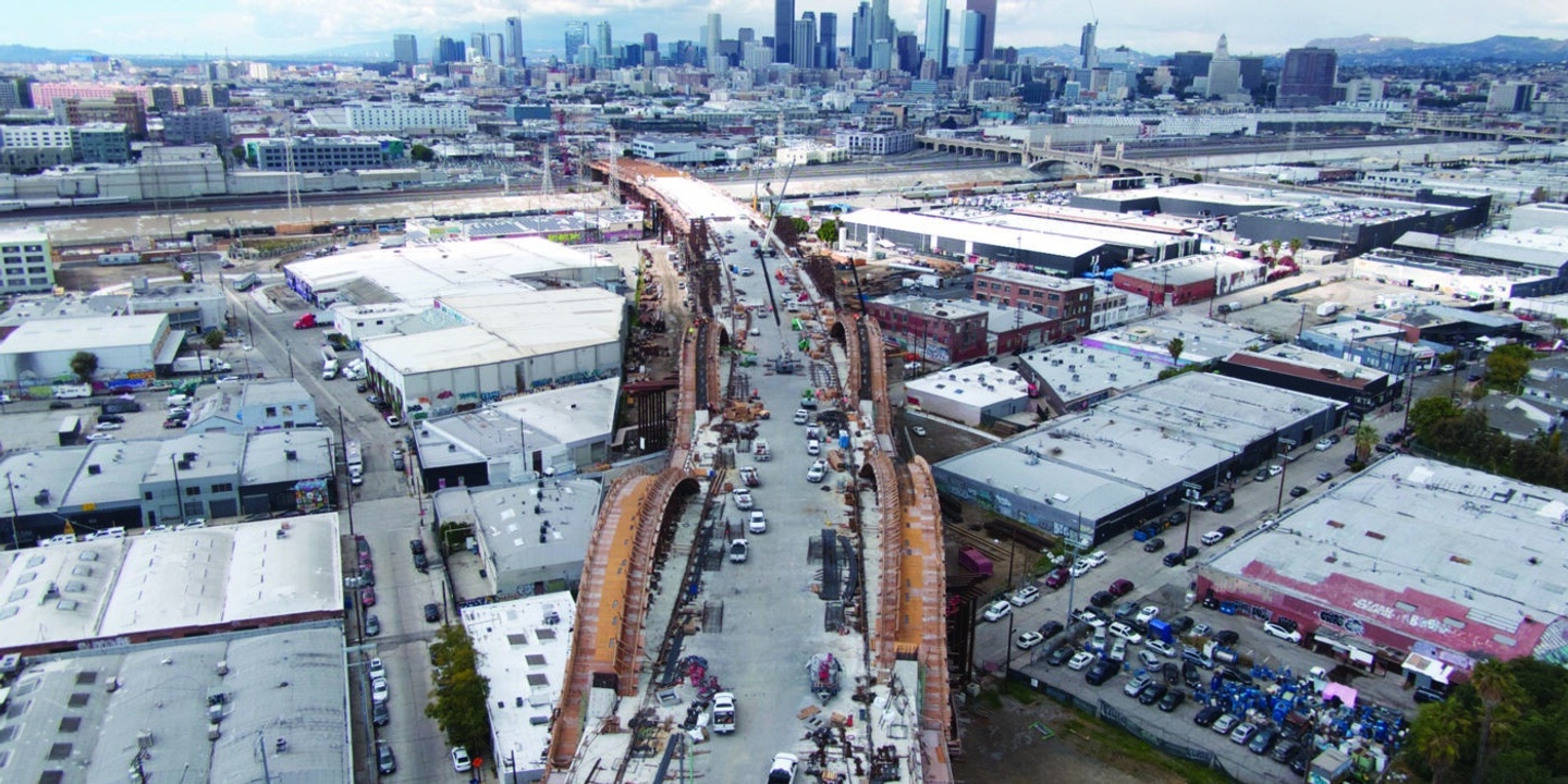 Aerial photo of construction work on a new viaduct project in Los Angeles, with the city skyline in the background.