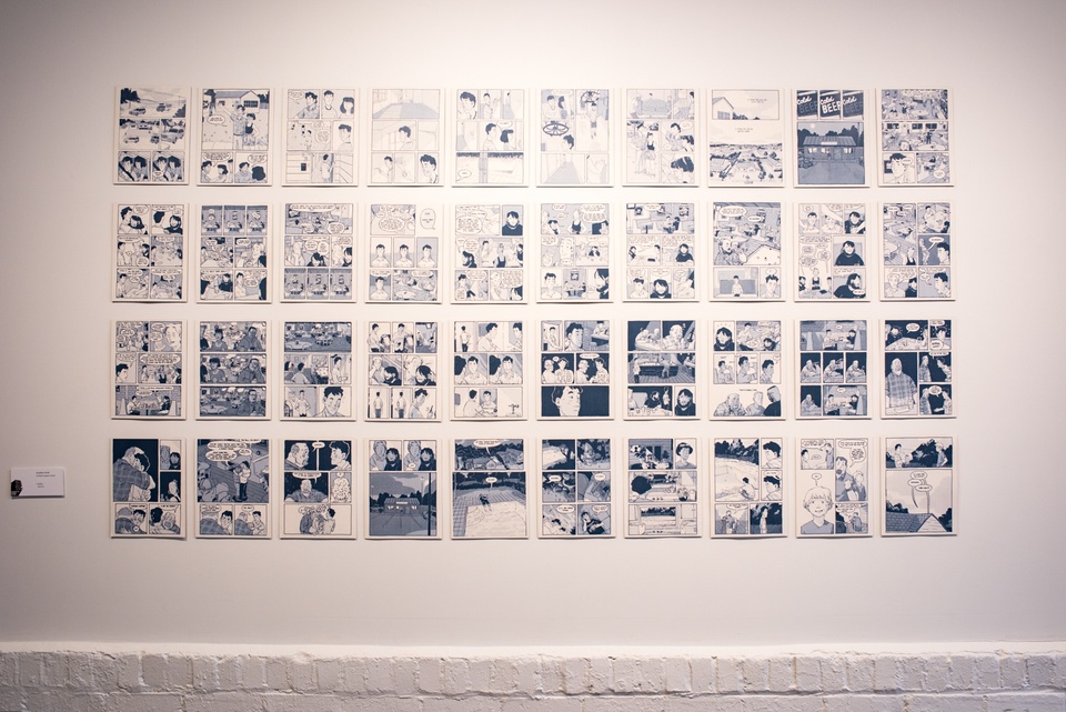 Forty comics pages printed in shades of blue on a wall.