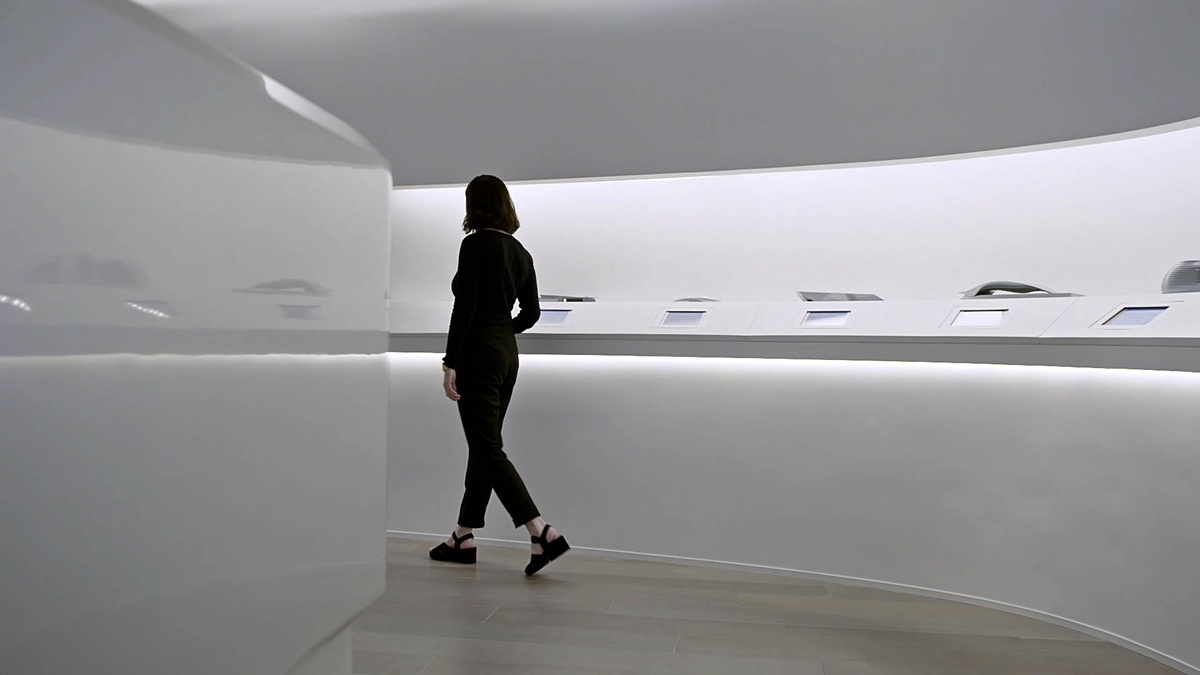 Woman walking through the realized sales gallery, in a curved hallway