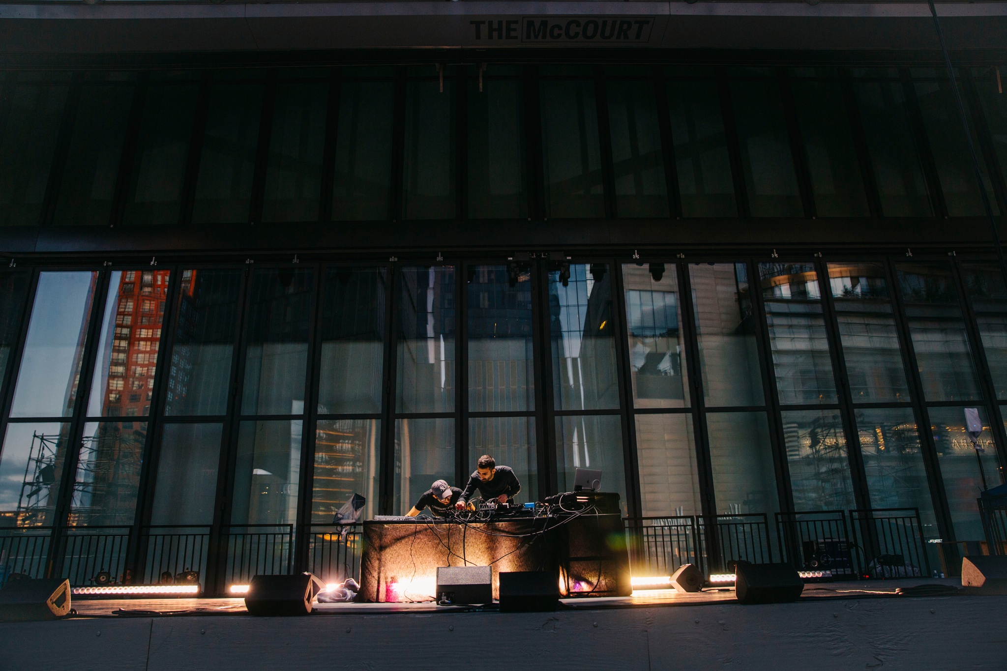 Two men behind an electronic DJ set up.