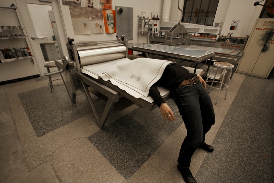 Photo of artist pretending to run herself through the printing press.