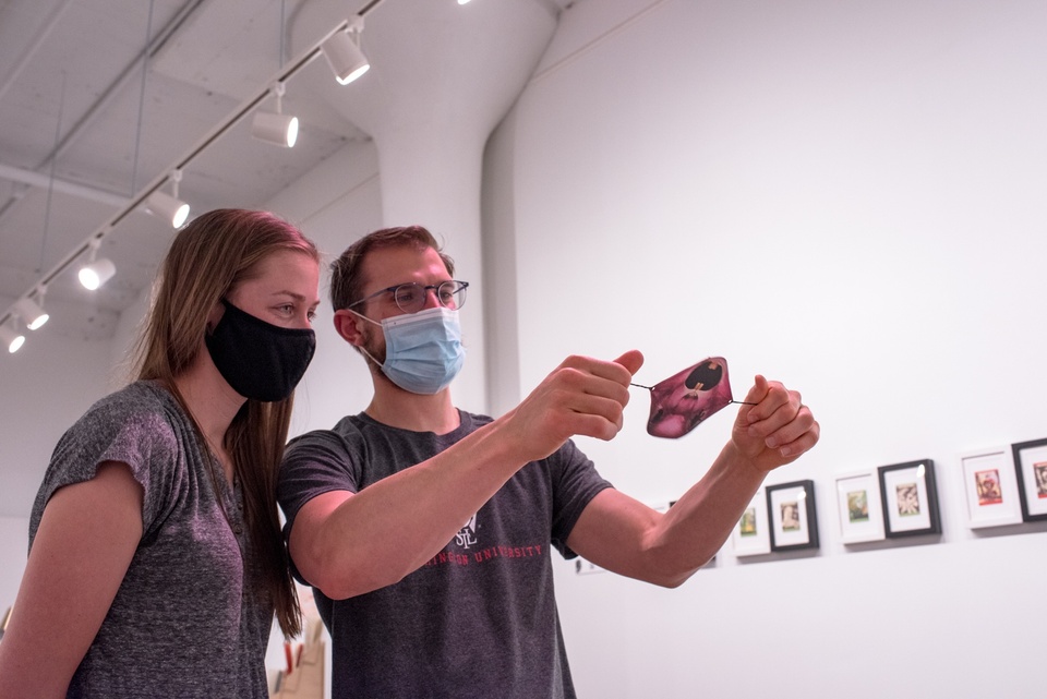 Two people in facemasks play with a thaumatope with an illustration of a snarling rabbit on one side of it.