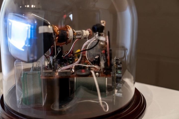 Close-up of a miniature cathode ray tube device inside a glass dome.