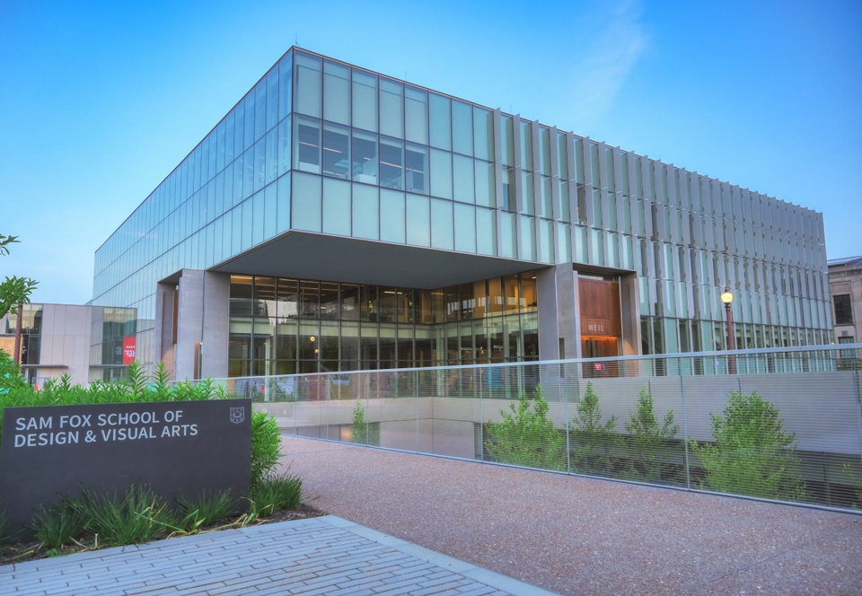 View of the cantilevered corner of Weil Hall. In front is a dark grey marble slab engraved with "Sam Fox School of Design & Visual Arts."