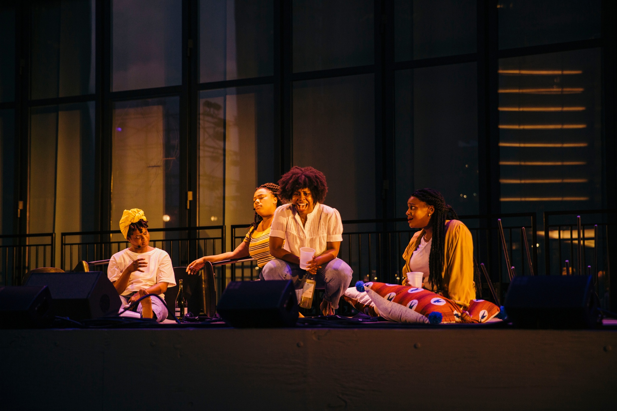 Four women sitting and acting on stage.