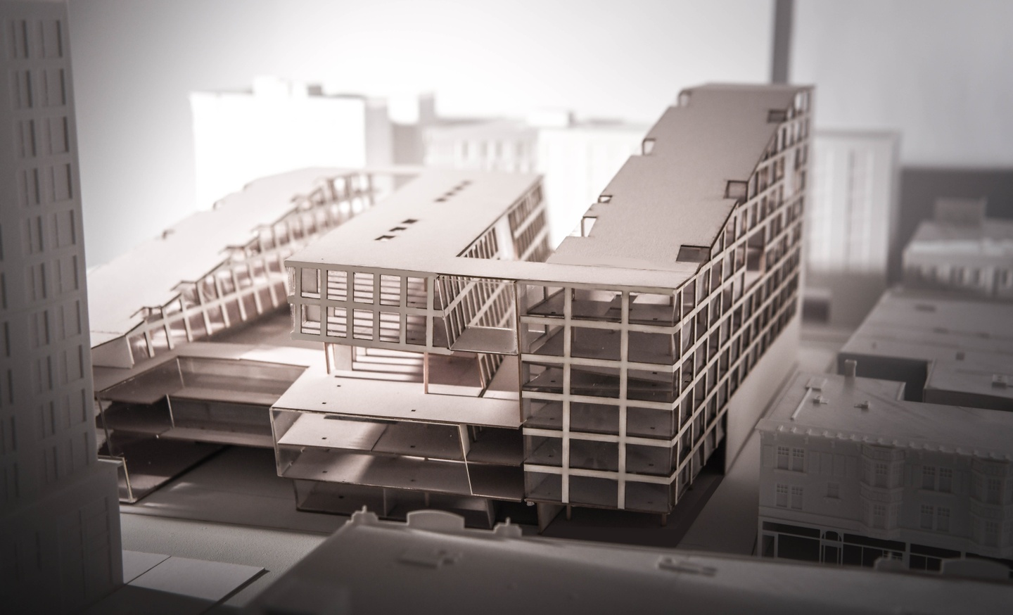 Scale model of basswood showing a multi-story office or apartment building. The building is in 3 segments and two of the segments have gently sloping roofs.