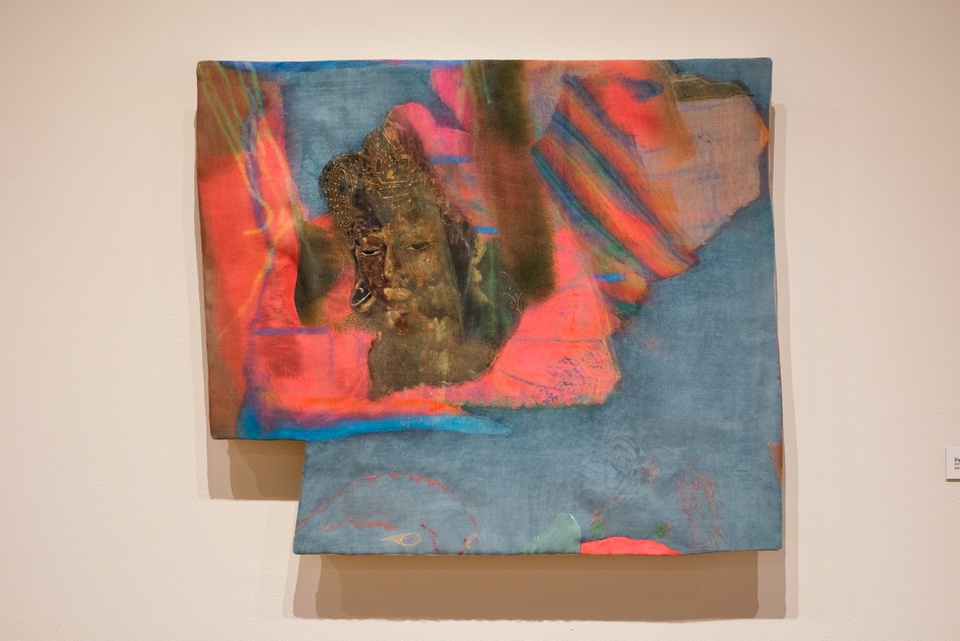 Painting of a blurred, sleepy-looking bronze head overlapping uneven shapes in rainbow and hot pink on a slate blue ground. The painting is wobbly rectangle shape with the bottom left corner trimmed out.