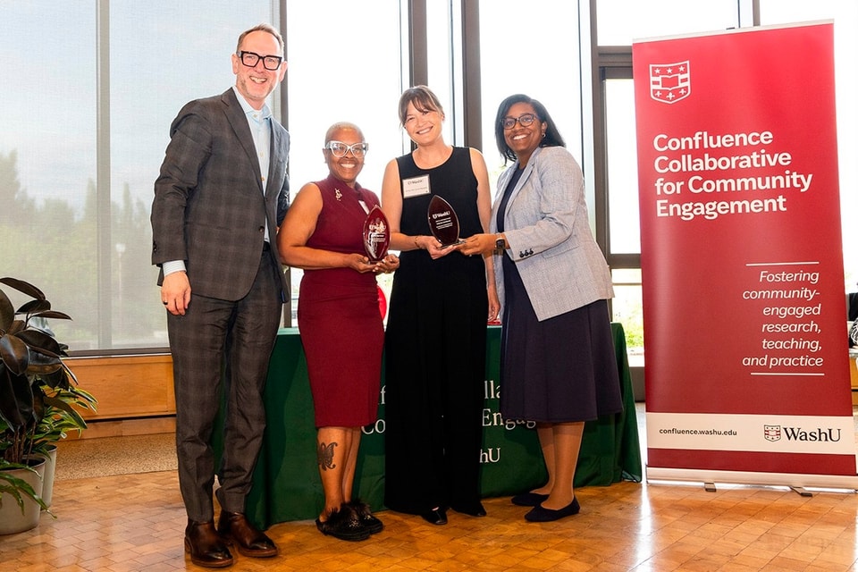 Four people standing next to each other with the two women in the center holding awards