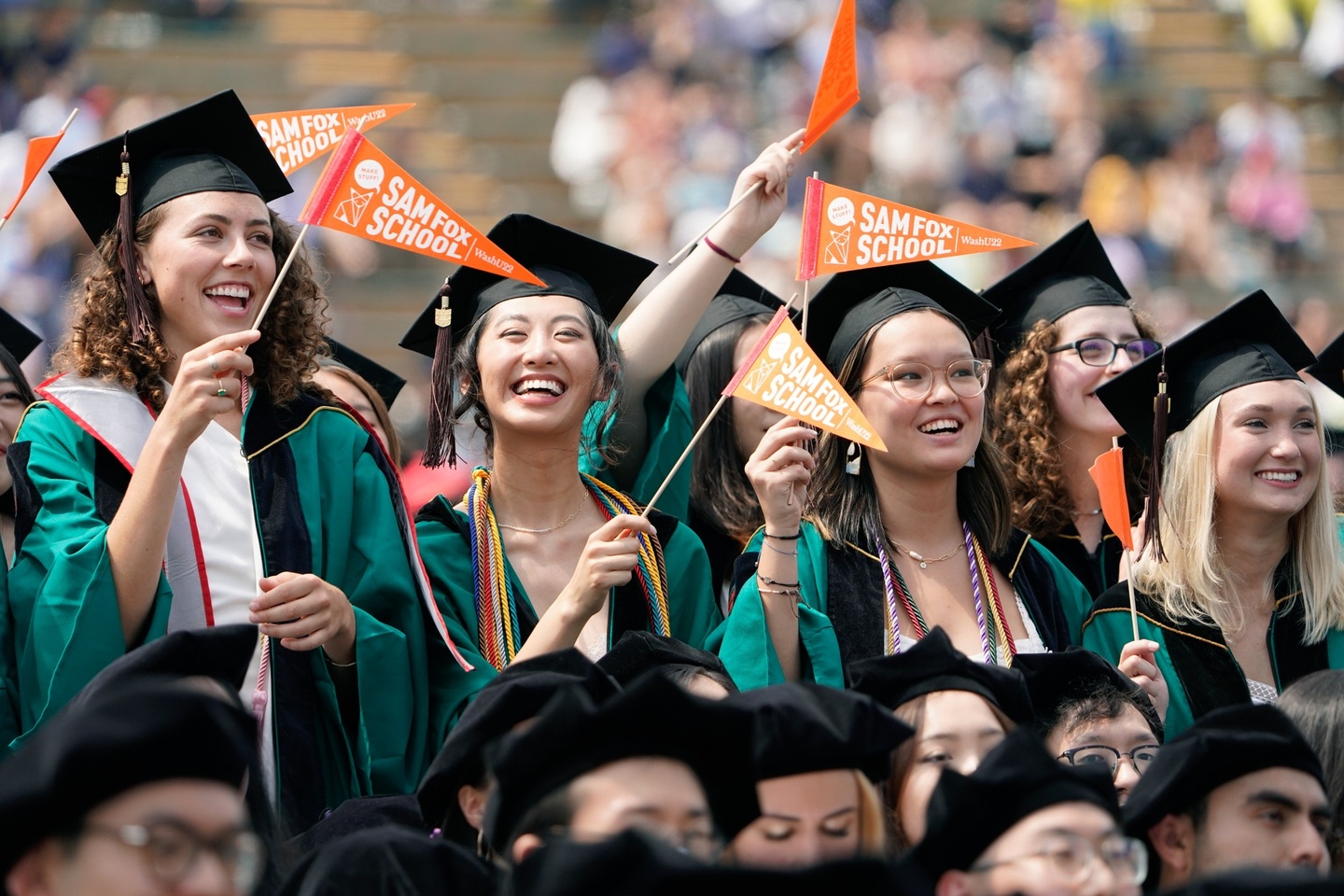 Students in green graduation robes and caps at the recognition ceremony.