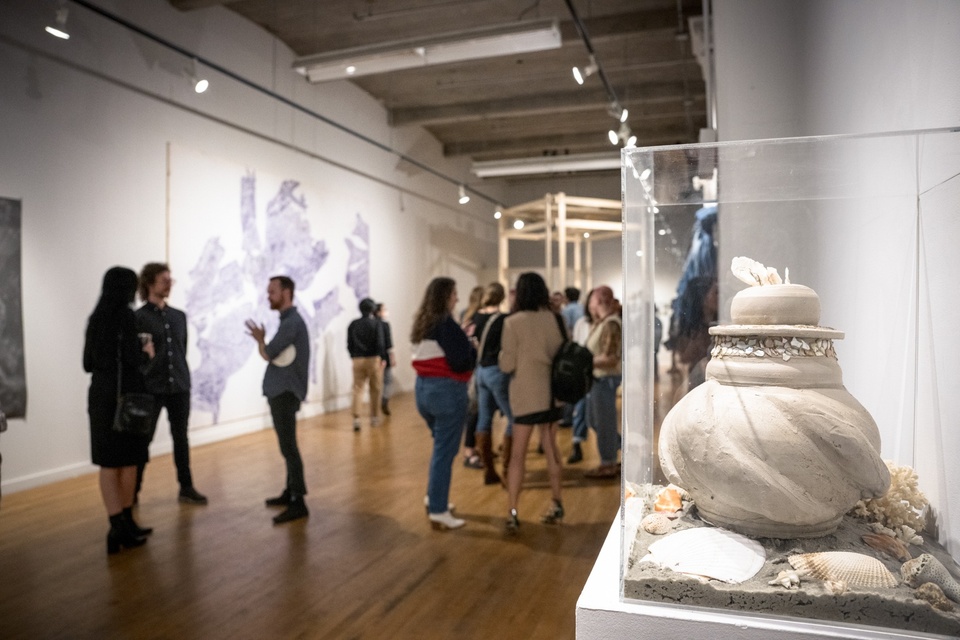 Exhibition view of visitors at the Des Lee Gallery, on the right Jamie Harris' unfired clay sculpture encased in a plexiglass box