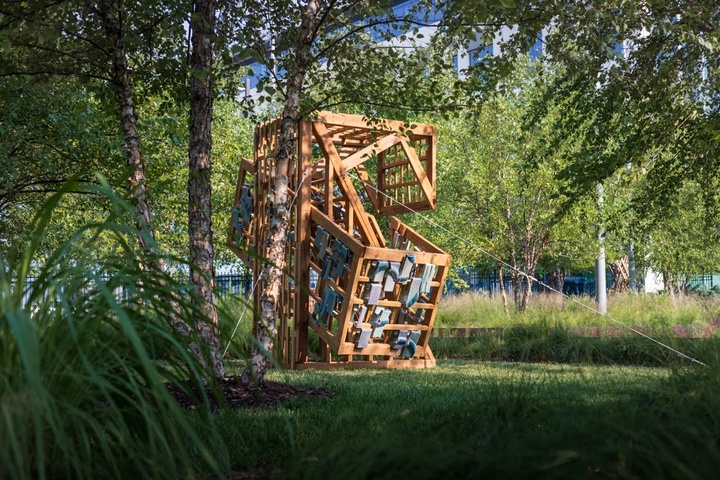 Wood and ceramic sculpture outdoors with native grasses and trees