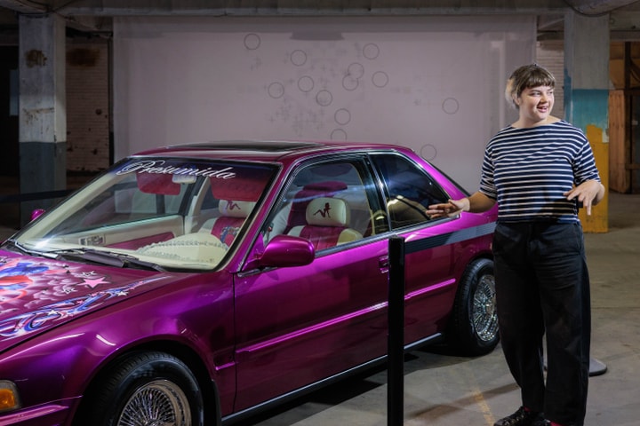 A woman in a striped shirt stands in front of artist Guadalupe Rosales's "slippin' into darkness" art installation.