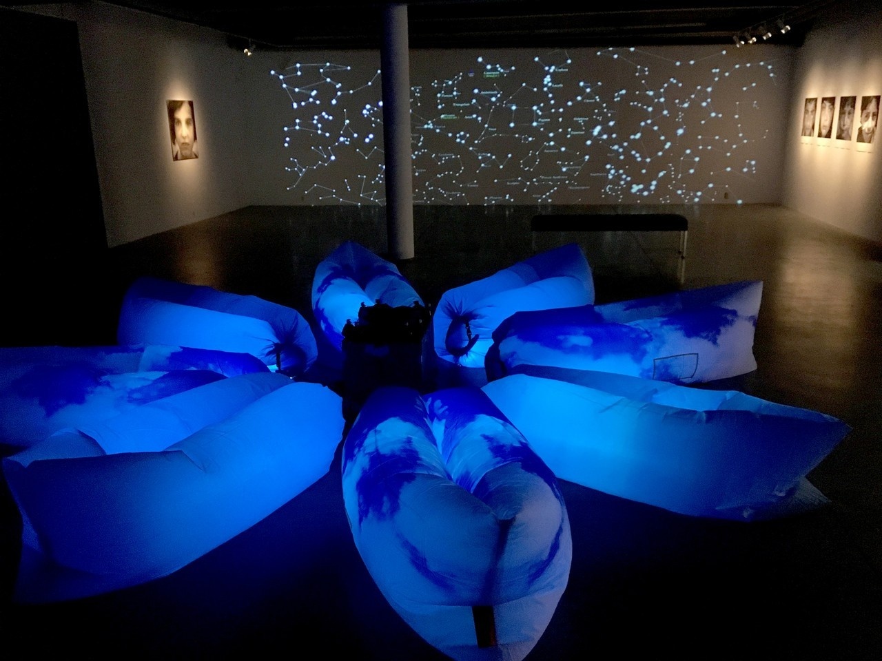   In the darkened central gallery, with a backdrop made of plastic gemstones and star projection, the installation features a lounging area with inflatable couches and equipped with motion sensors, speakers and LED lights.
