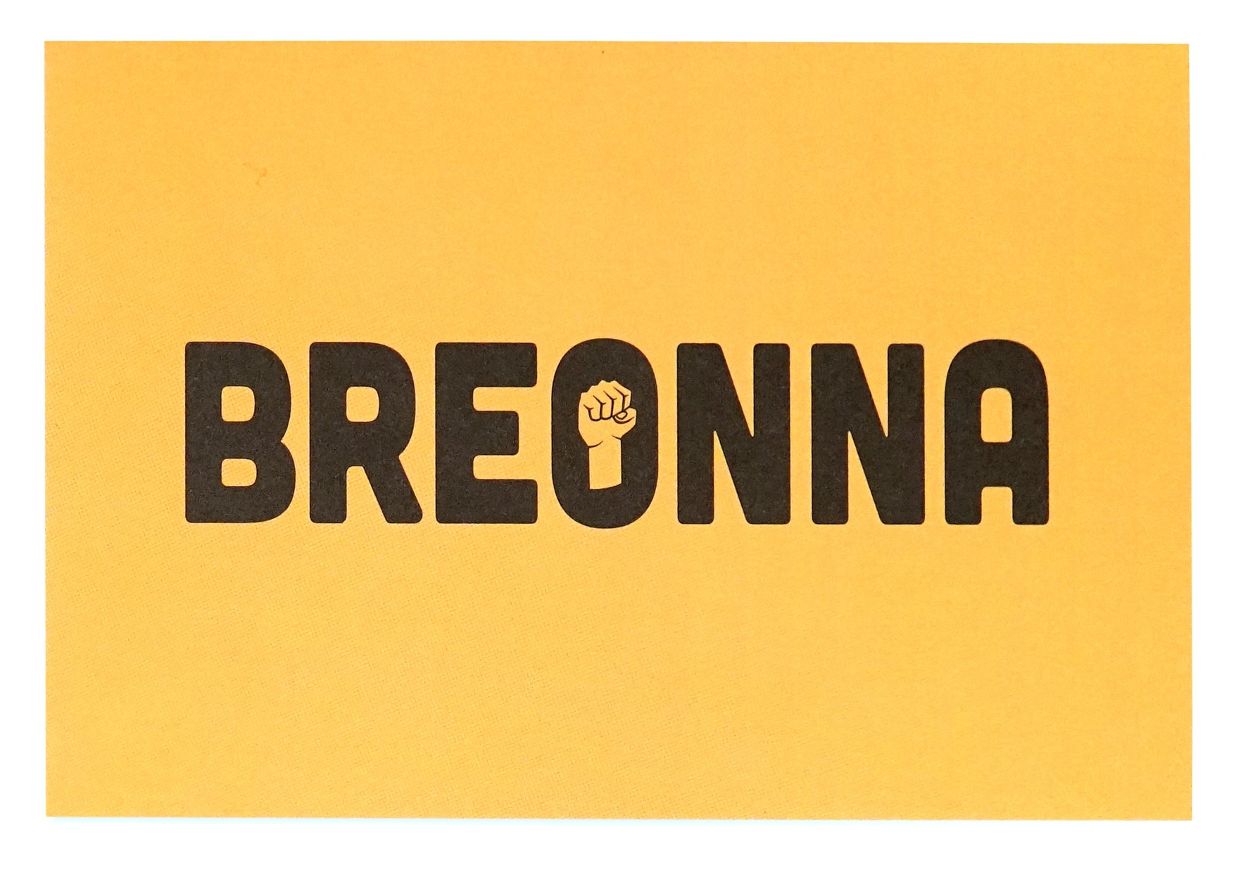Black text "BREONNA" printed on yellow paper. The center of the "O" is a raised fist.