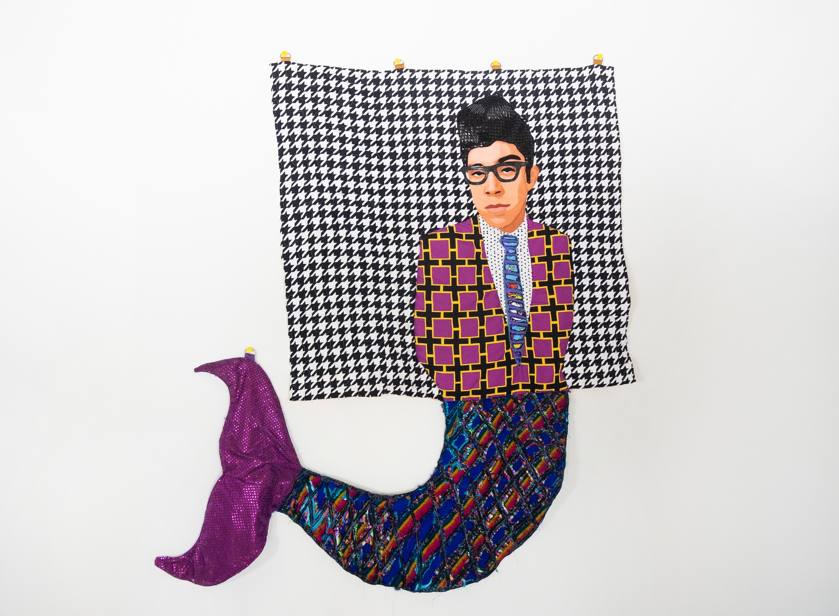 A collage portrait of a Latino man wearing a tie and plus-signed-pattern jacket on a patterned background, with a sequined blue and purple mermaid tail extending below his torso. 
