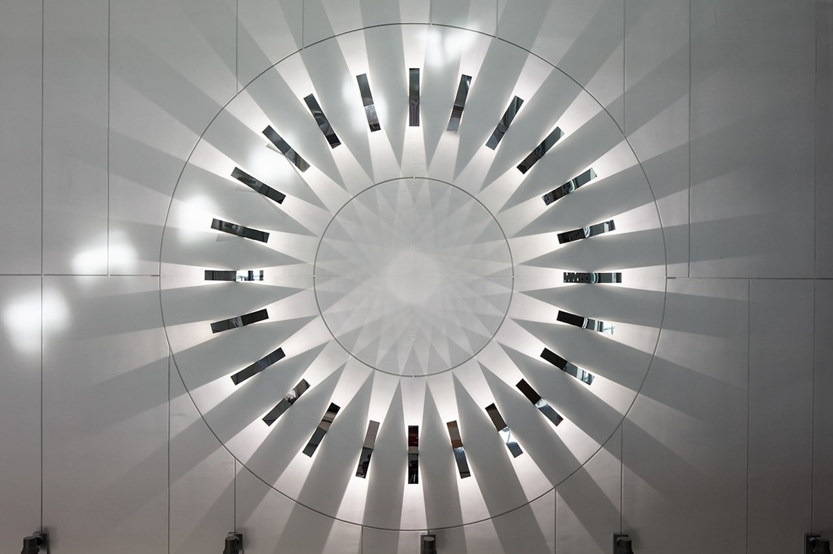 Photograph of circular metal sculpture with light radiating inward and outward in circle