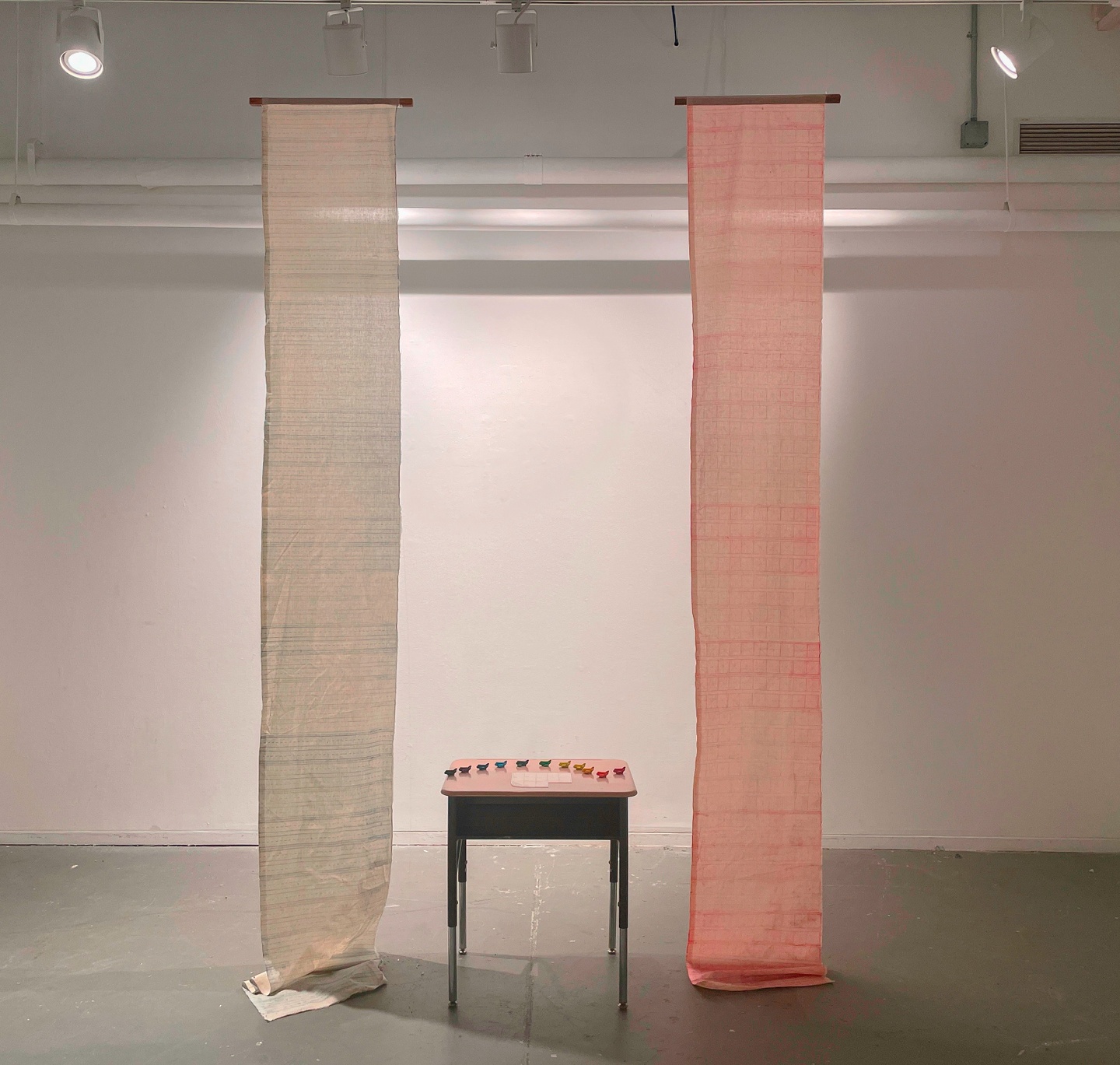 A desk with small rainbow planes and a pink and white tapestry hanging on either side. 