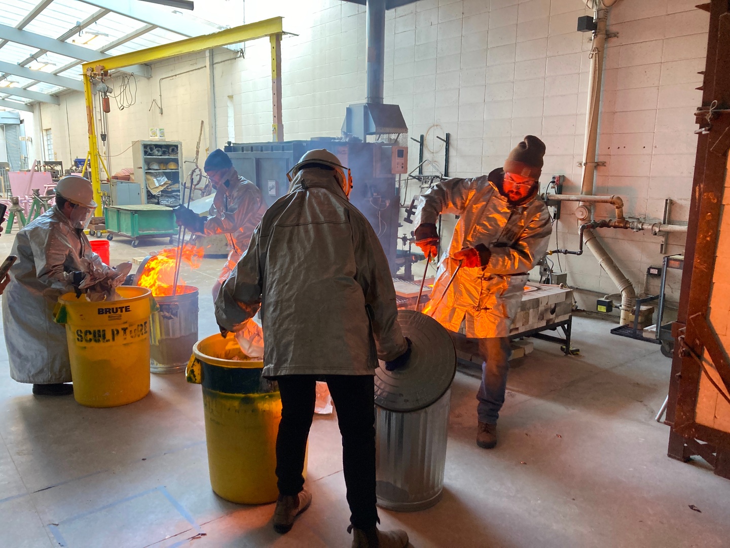 faculty and students wearing protective gear and using raku fire technique for ceramics 