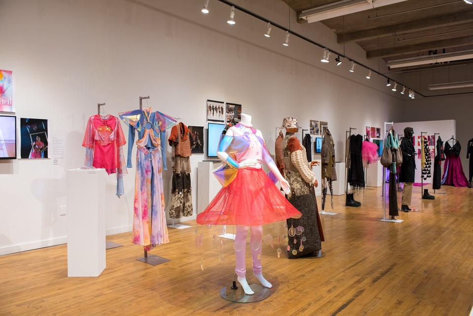 View of a gallery with a variety of garments displayed on mannequins.