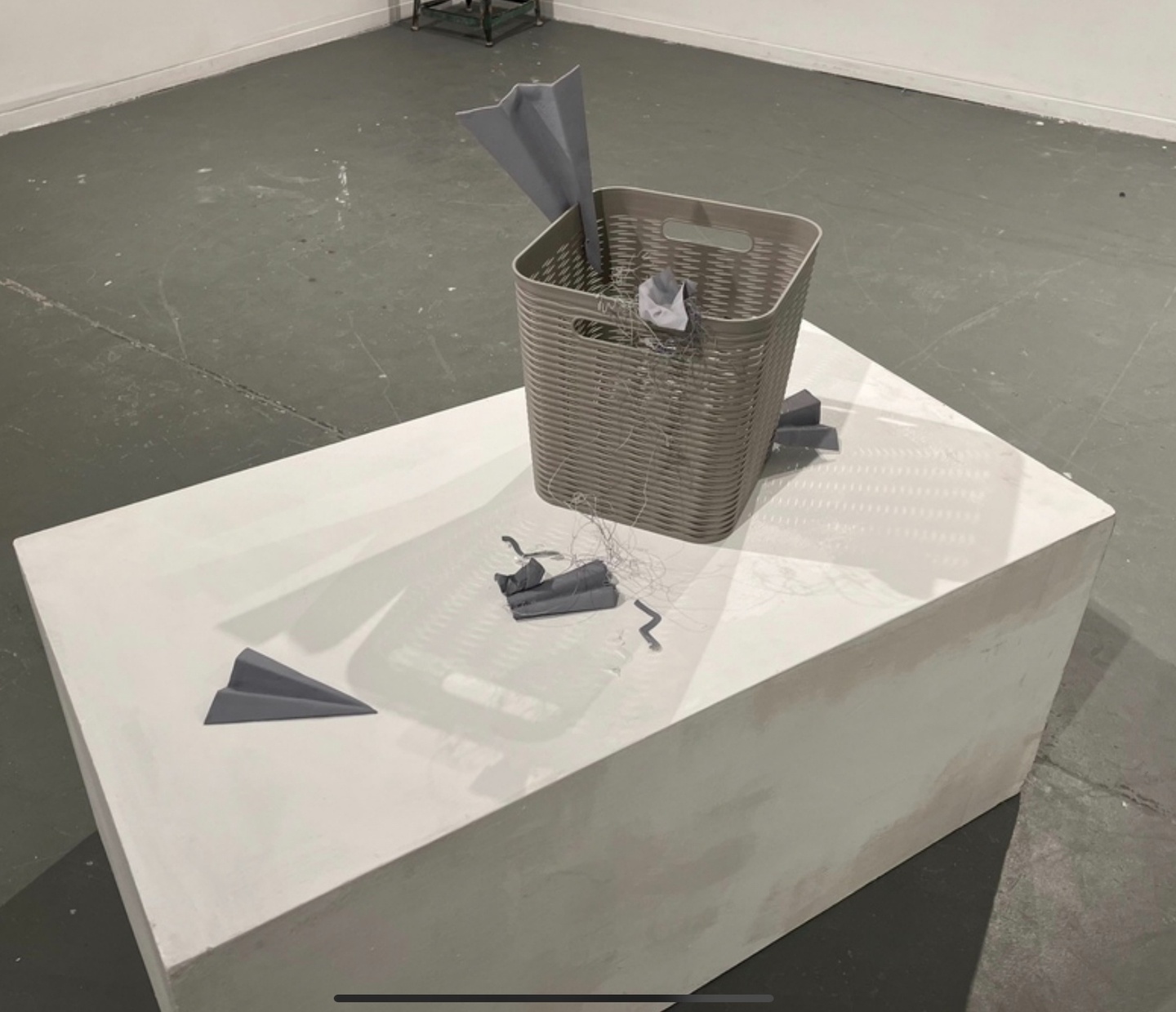 A sculpture of paper planes interacting with a bin.