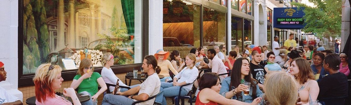 A crowd of people eating at patio tables outside a restaurant