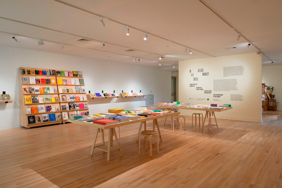 spacious white room with light wood flooring and book lined shelves and tables