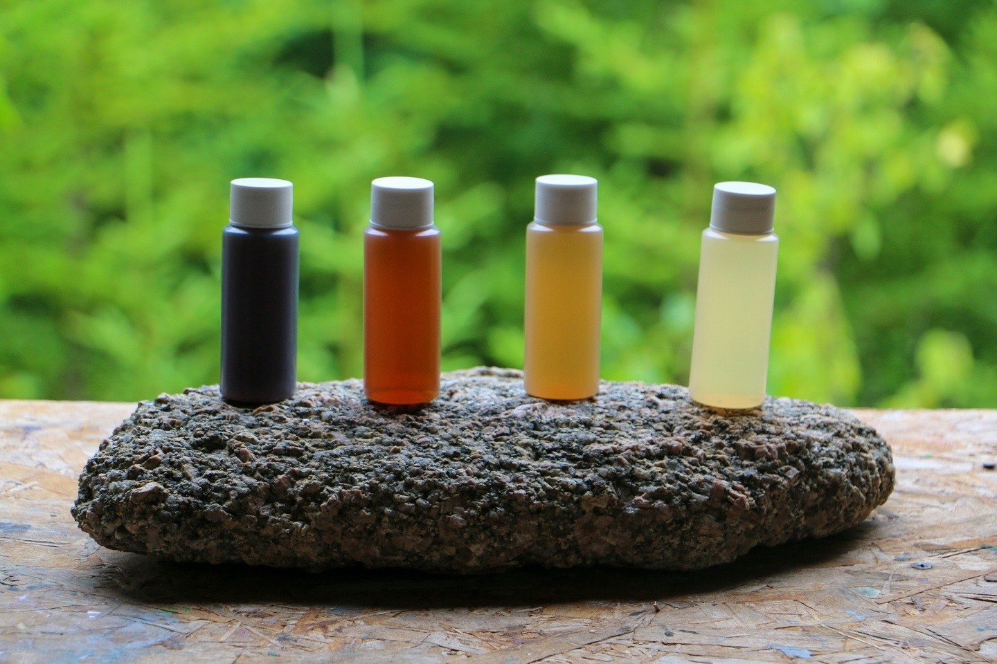 4 mini bottles of various shade of brown resting on a flat stone