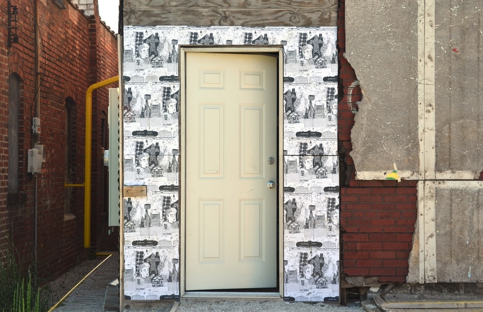 Image of a doorway with black and white illustrated artwork pasted around the wooden panels surrounding it