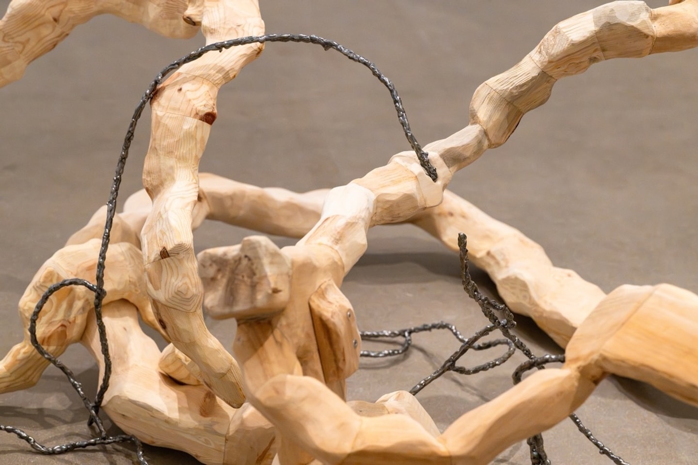 carved wooden pieces fitted together in an endless twisted configuration on display in a gallery