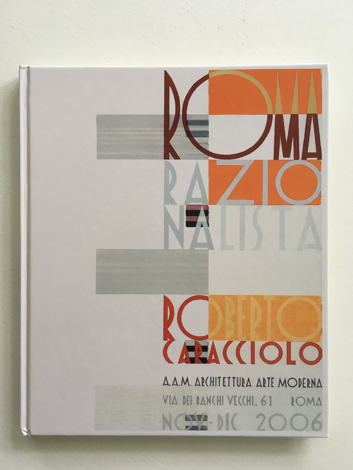 Cover of Romo Razionalista, Roberto Caracciolo, featuring orange, gray, and orange triangles and burgundy, gold, gray, and red lettering.