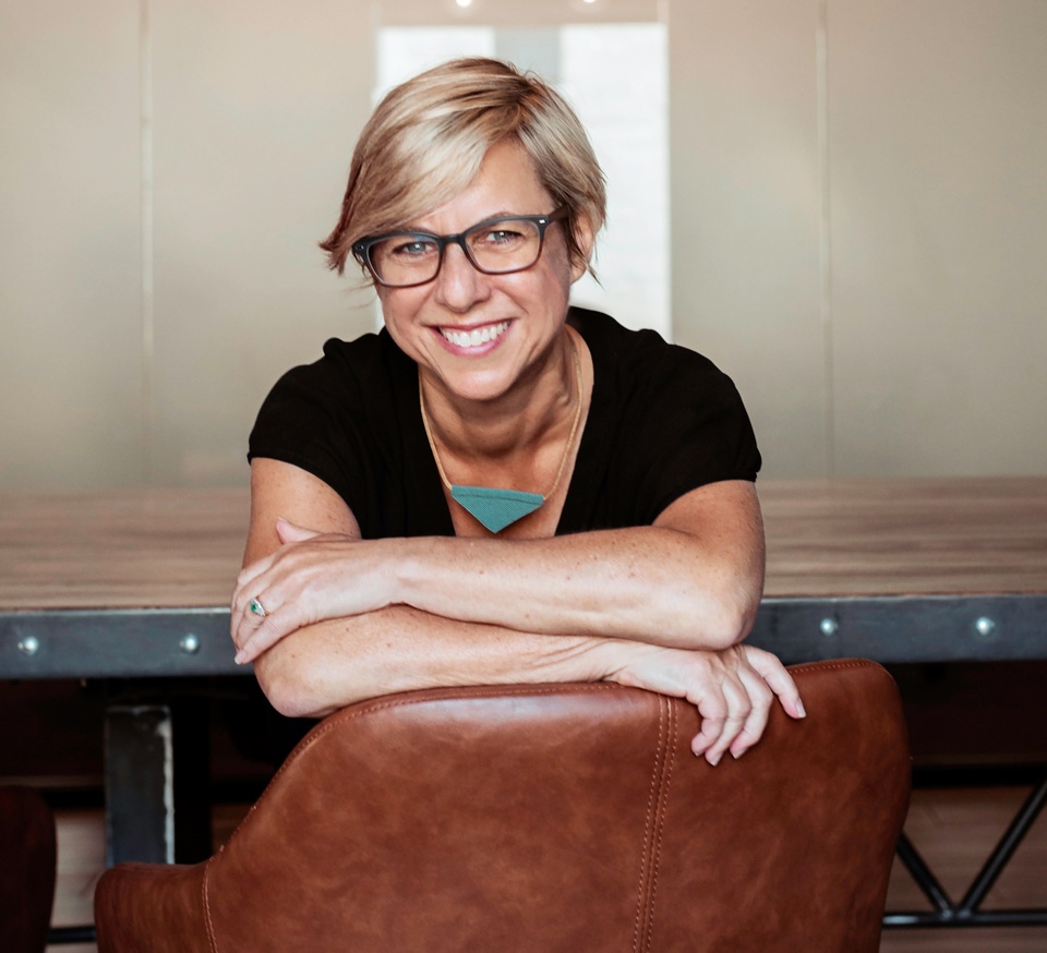 Professor Linda C. Samuels resting arms on back of chair smiling at camera