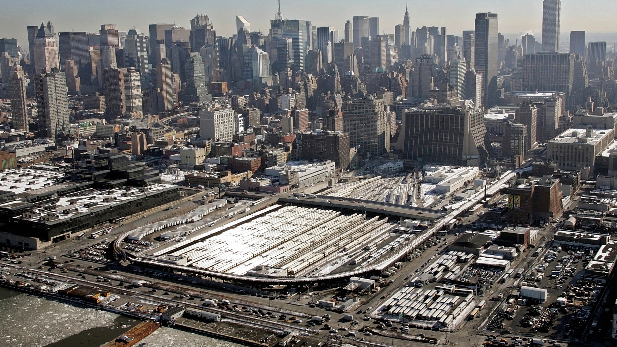 The New York skyline seen on a sunny day from the west side above the Hudson River. Prominent in the foreground are the rail yards covering multiple blocks before the development of Hudson Yards.