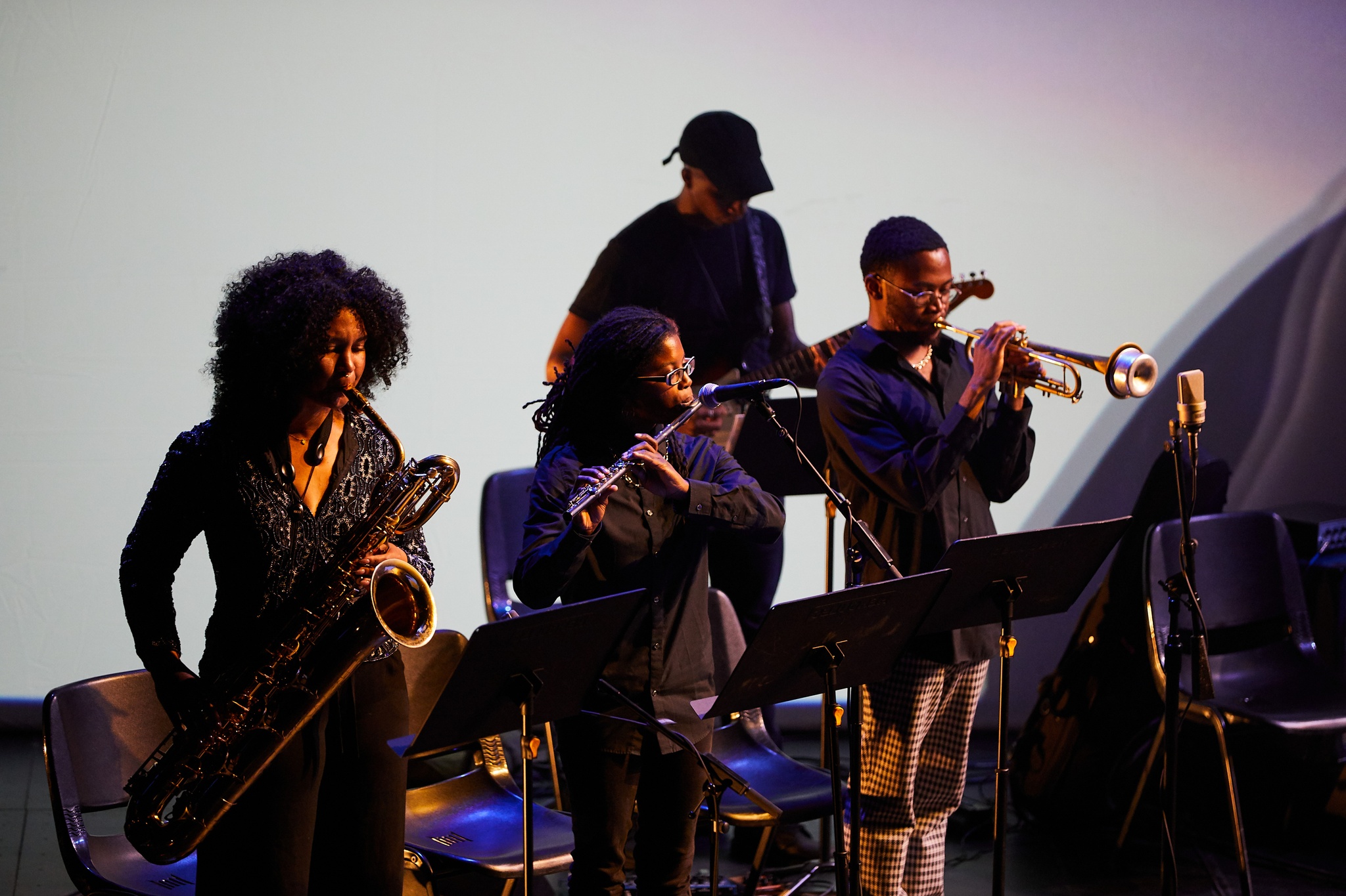 Four musicians standing on stage while playing.